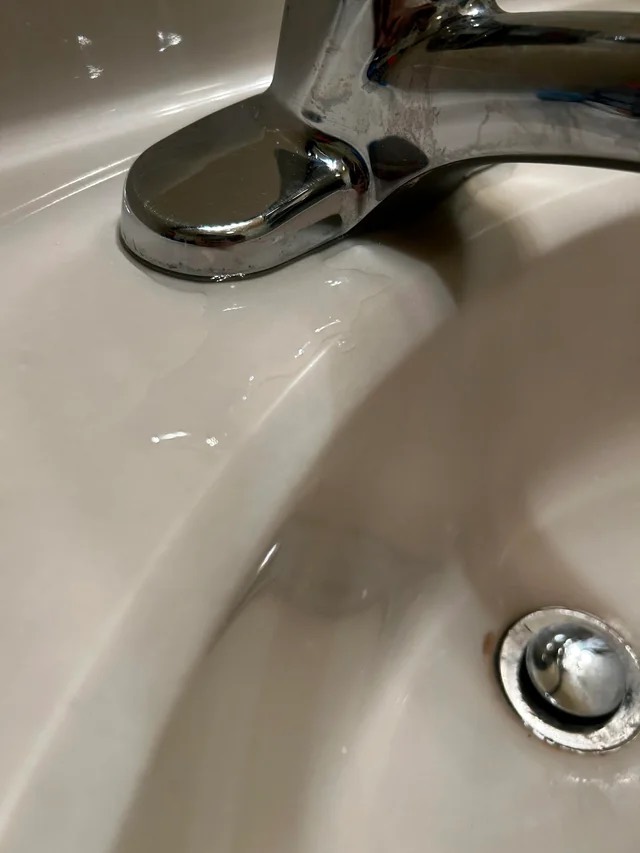 Customer photo of a bathroom faucet with water pooling around its base